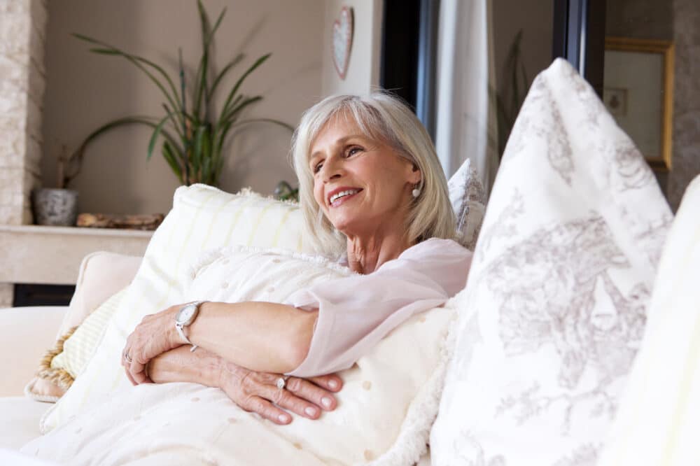 A close up portrait of a happy older woman sitting on a couch relaxed